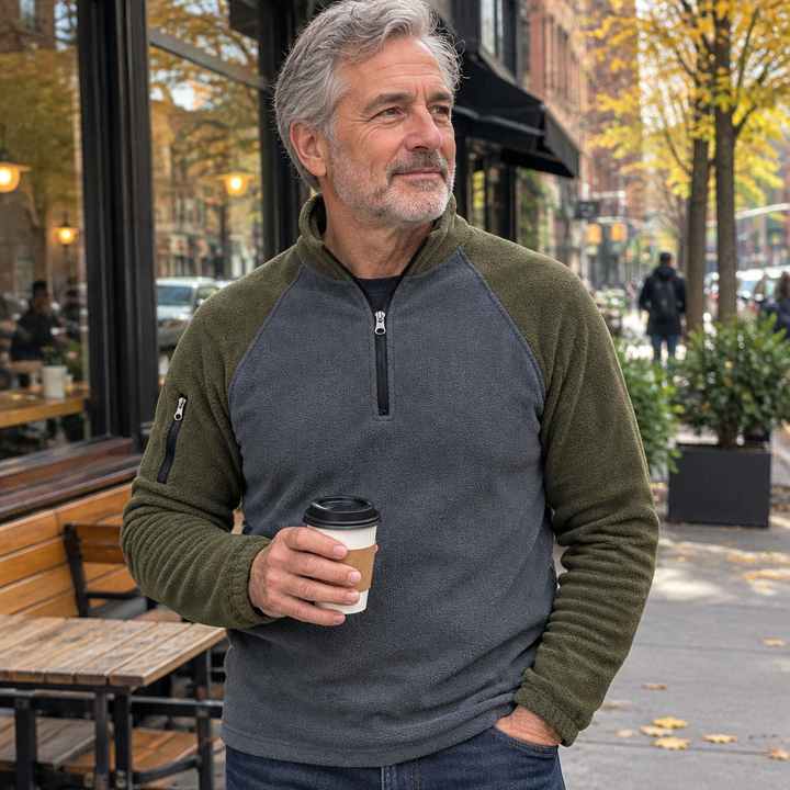Man in a two-tone half-zip pullover holding a coffee